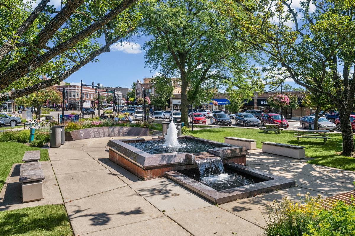 The fountain in downtown Wilmette, with storefronts and shade trees behind it