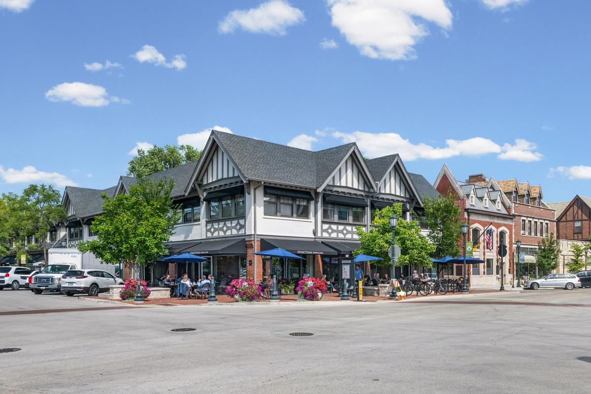 Storefronts and outdoor seating on Elm Street in downtown Winnetka, beneath the Tudor building on the corner